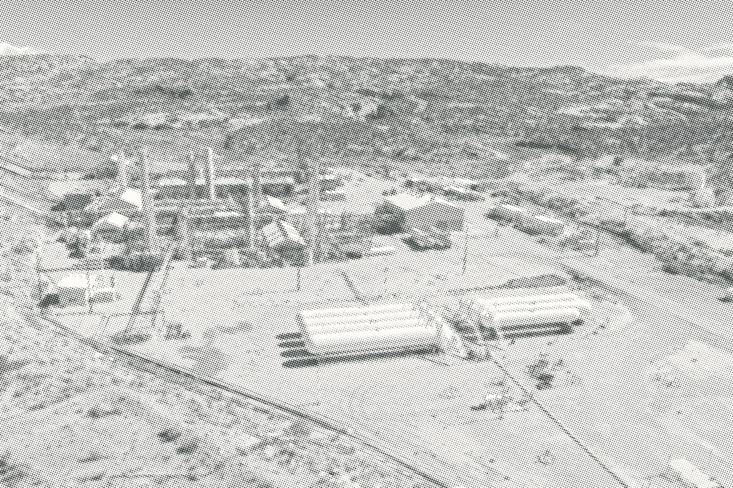 Aerial photograph of the physical plant, access roads and surrounding land, screened as a halftone.